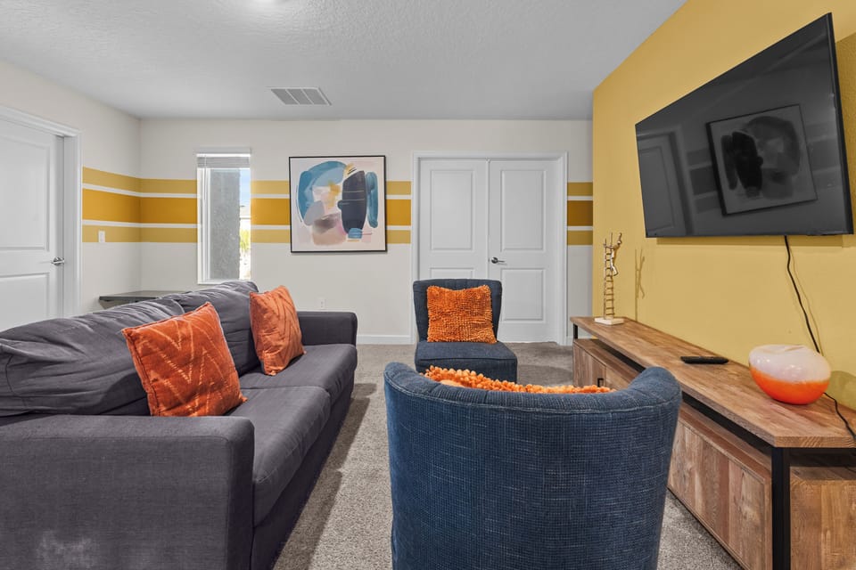 Settle into your stylish lounge with vibrant orange accents, plush seating, and entertainment center for perfect movie nights.