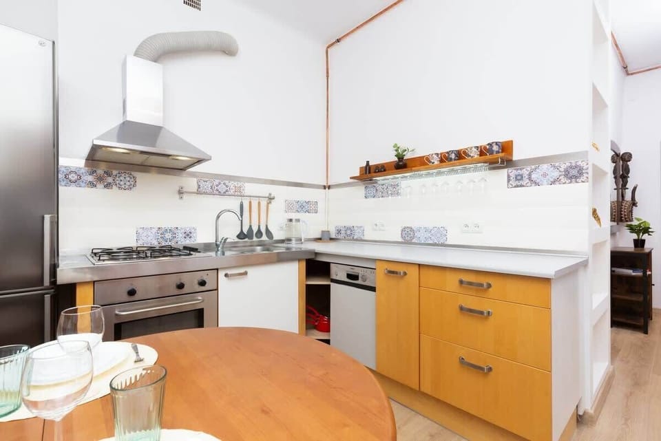 A modern kitchen with warm wood cabinetry, open shelving, and natural light streaming in.
