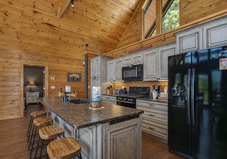 Your fully equipped kitchen features granite countertops, modern appliances, and a spacious island for cooking memorable meals in this warm log cabin setting.
