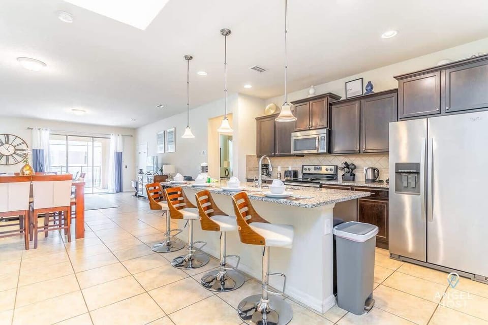 A spacious kitchen designed for both cooking and casual dining, with a bar and four stools.