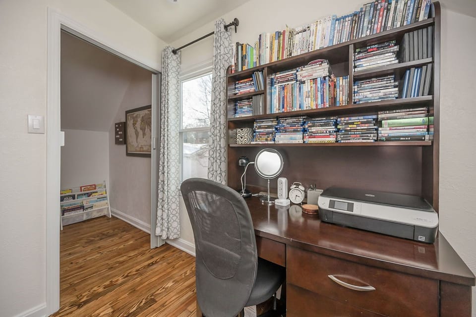 There is a desk with a printer and lots of Dvd"s