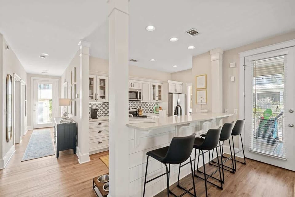 - Bright and functional kitchen with a spacious breakfast bar and room for everyone - Clean lines, coastal backsplash, and bar stool seating blend style with comfort - Open layout flows into the hallway, keeping the space social and welcoming