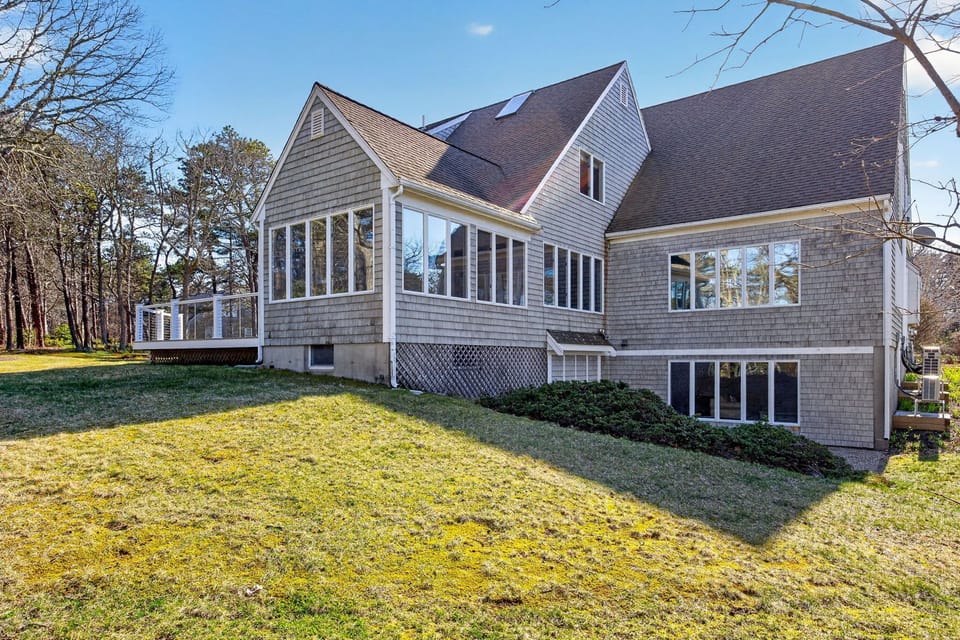 Classic shingled home nestled among mature trees with spacious lawns and large windows throughout.