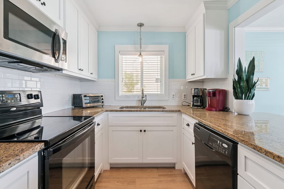 Step into your fully equipped kitchen featuring granite countertops, stainless appliances, and cheerful blue walls that make meal prep feel like a breeze.