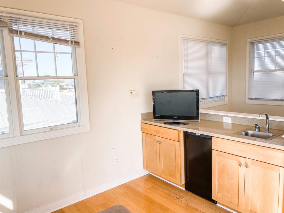 A full bar with wet sink, refrigerator, and TV create an adult space for drinks.