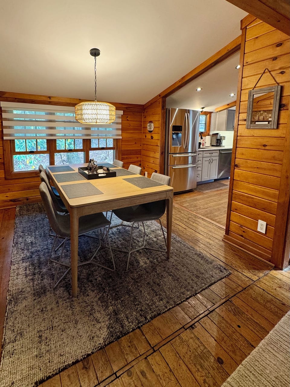 Cozy cabin dining room for six with chic lighting and wooded lake views