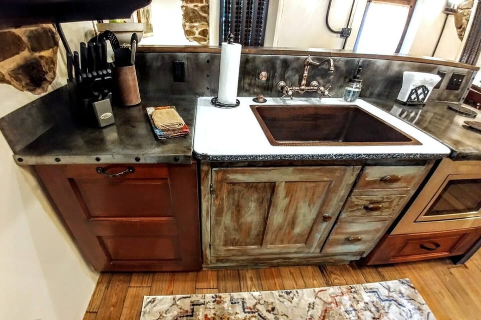 Main level kitchen on this historic home's upper level features a large porcelain sink and dishwasher cleverly disguised as a cabinet on the left