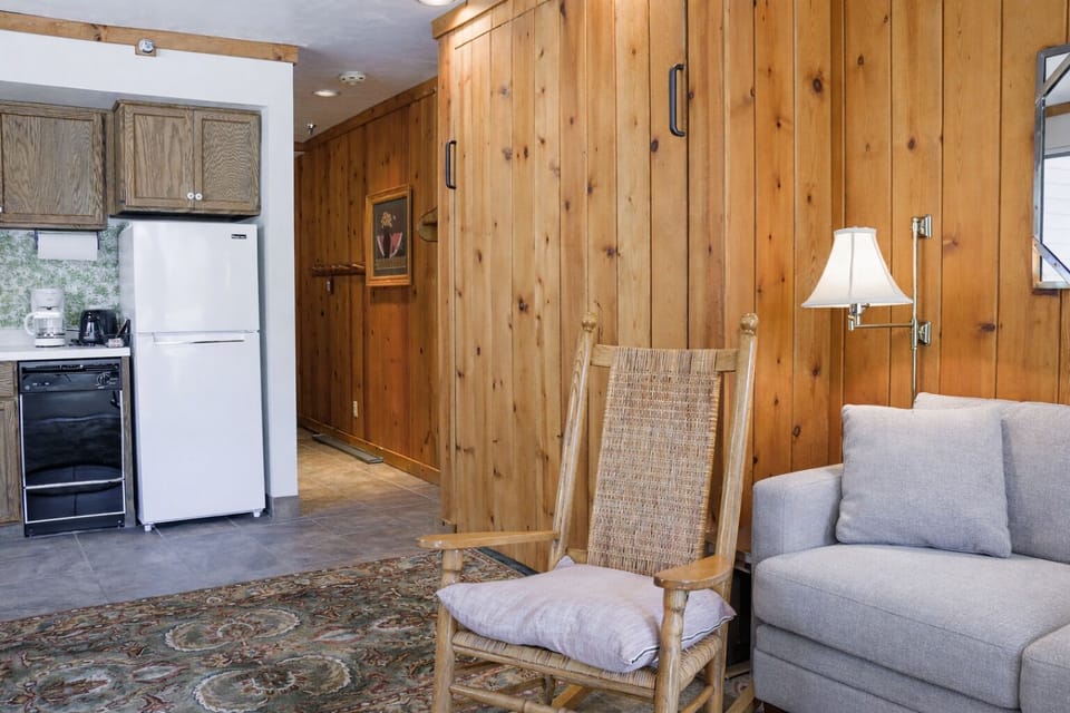 Cozy mountain living room with a stone fireplace, comfy sofa, and balcony access.