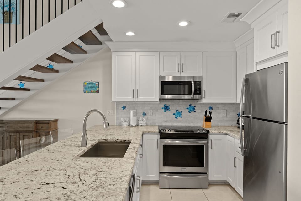 Your bright, modern kitchen features granite countertops, stainless steel appliances, and charming coastal decor—perfect for preparing meals or brewing morning coffee in your home away from home.
