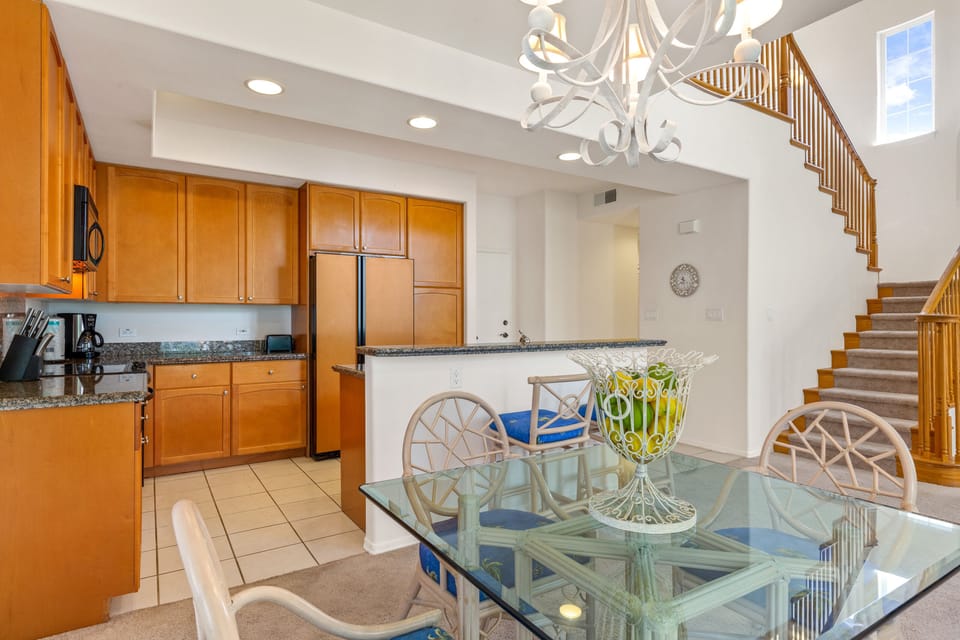 Bright, airy living space where you'll love gathering for meals under the elegant chandelier, with a fully equipped kitchen and soaring ceilings that create an inviting, spacious atmosphere.