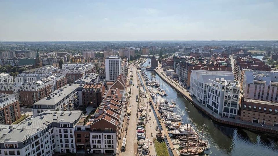 A wide aerial view of the neighborhood, showing streets, residential buildings, and green spaces, giving context to the apartment’s location within the city.