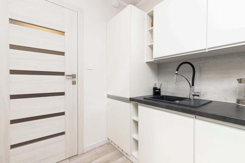 A different perspective of the kitchenette, showing additional white cabinetry, a black sink, and high-quality fixtures that reflect a modern, minimalist design.