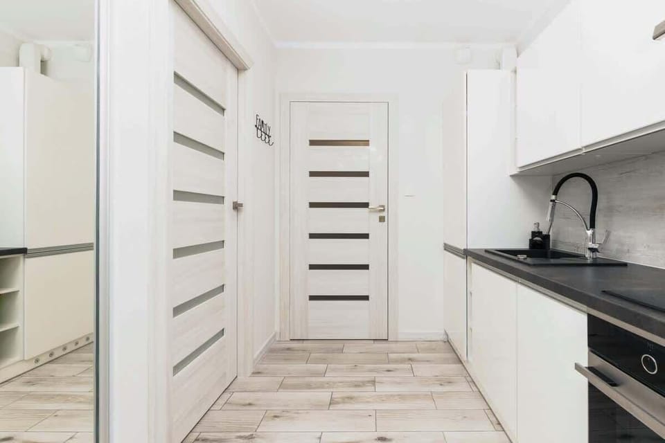  close-up view of the kitchen area with white cabinets, a black countertop, and modern appliances. The cabinets have a handleless design, enhancing the sleek, seamless look.