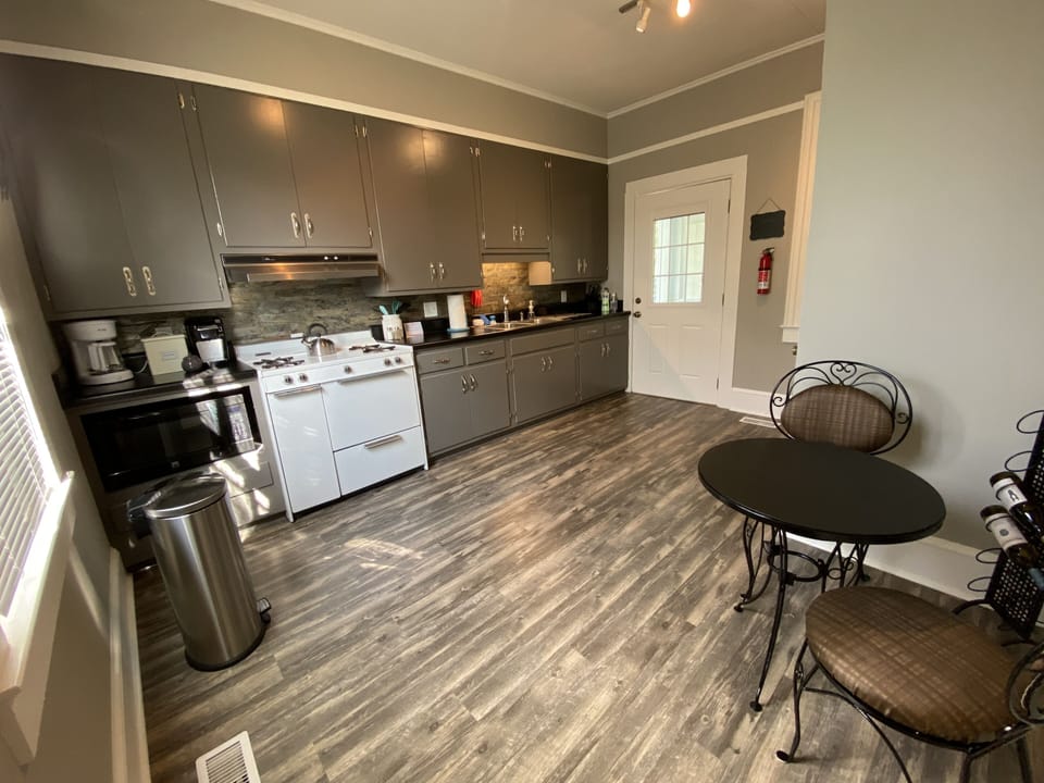 Open kitchen with gas range and oven, coffee station, & cafe table
