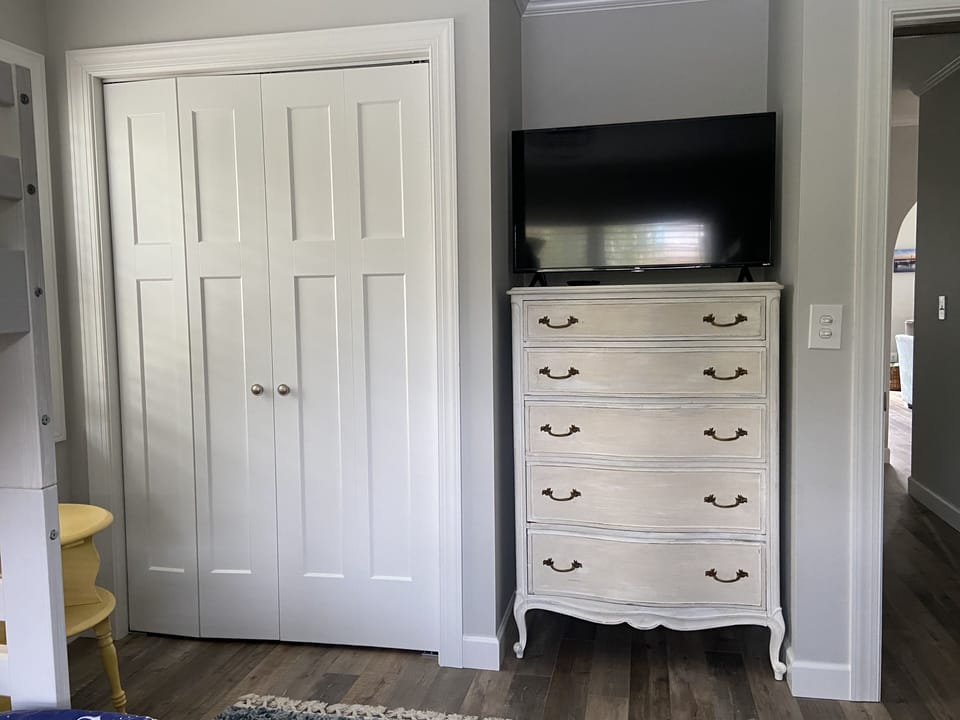 Bunk room w/ Smart TV, dresser, and closet with pack-n-play, high chair, & gate