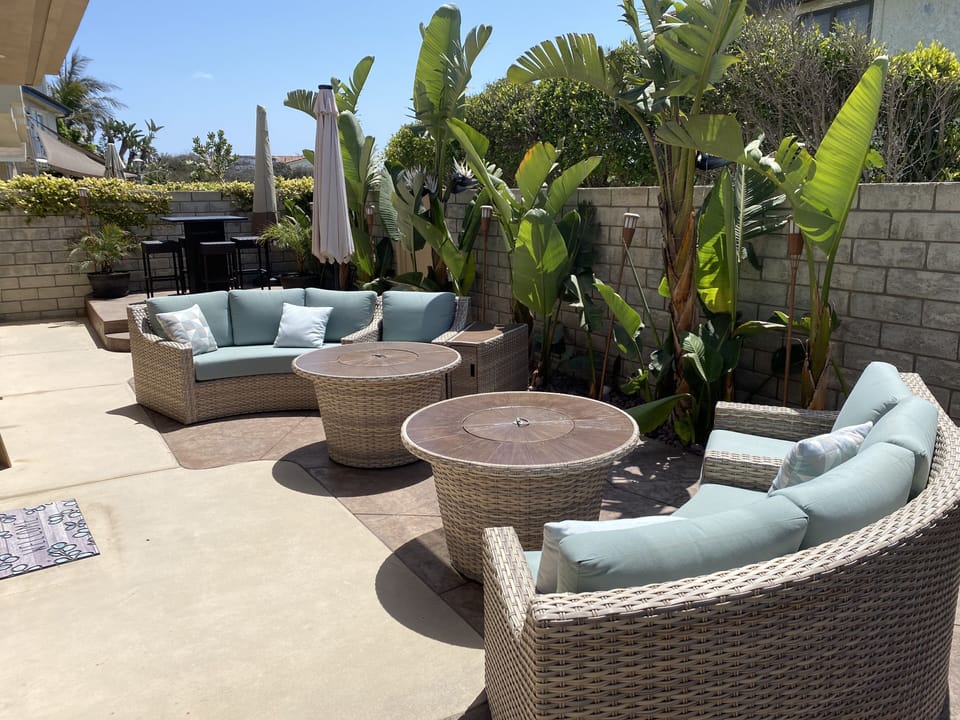 Two separate seating areas each with a firepit and umbrellas for shade