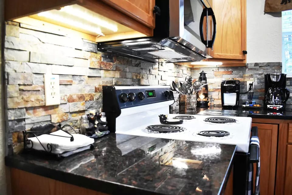 The rock backsplash and granite counter tops add a rustic touch to the kitchen.