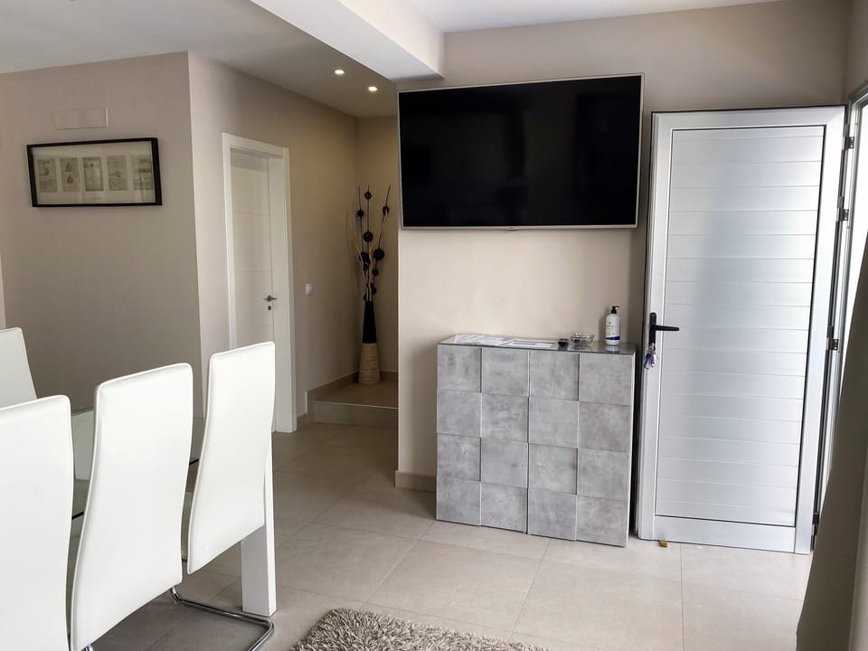 View showing stairs to upper floor and Smart TV with English channels on wall 