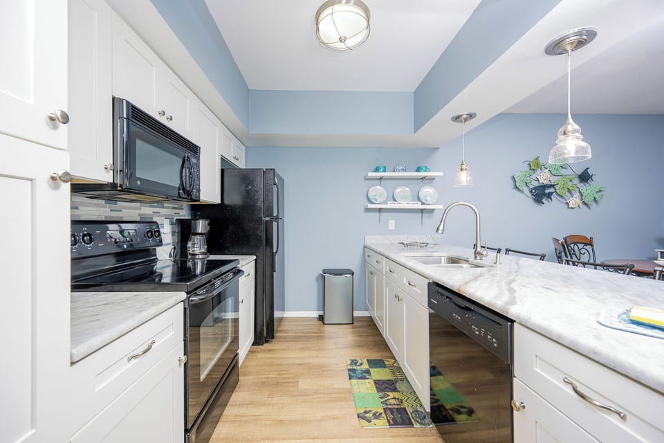 The kitchen features sleek black appliances, a stylish countertop, and decorative accents for a cheerful cooking experience