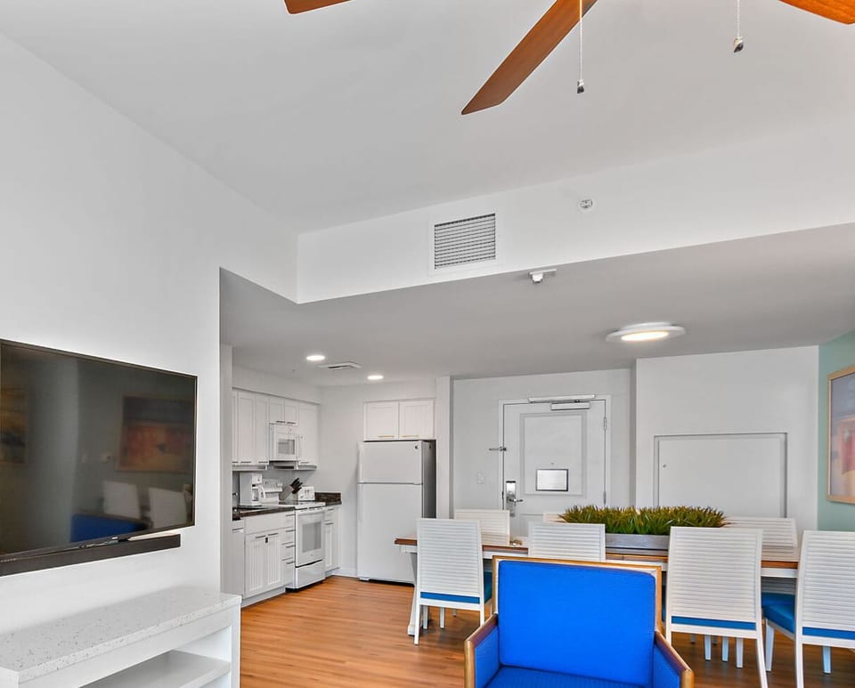 wall-mounted flat screen TV with open living/dining/kitchen areas