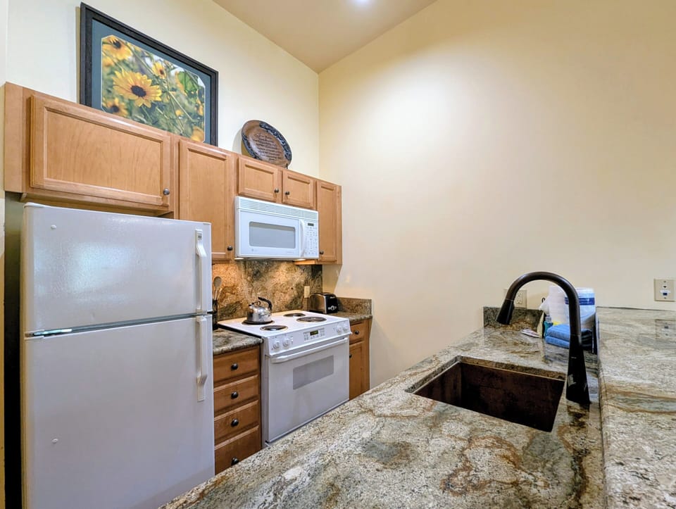 Your fully equipped kitchenette features granite countertops, stainless sink, stove, fridge, and microwave—everything you need to prepare meals during your stay.