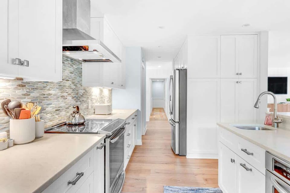 Your dream kitchen awaits with gleaming white cabinets, stunning tile backsplash, and premium stainless steel appliances ready for culinary adventures.