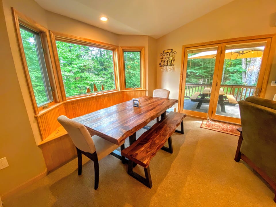 Dining/Living Area: Open concept space with a warm wood dining table that seats 8 and comfortable furniture that surrounds the stone fireplace.