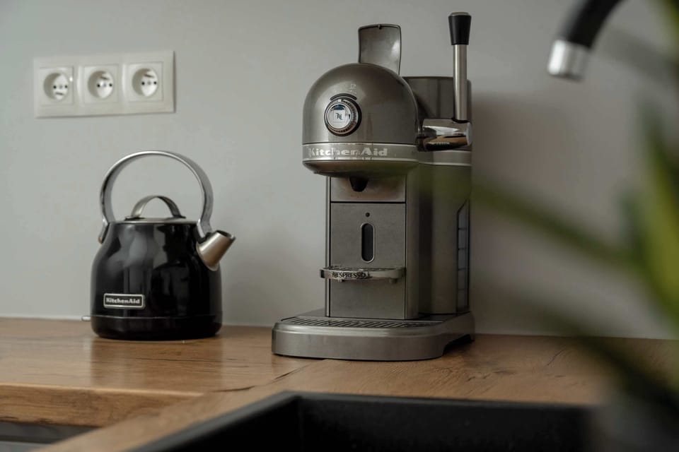 Coffee machine and kettle on wooden counter – Morning essentials in a stylish kitchen corner.
