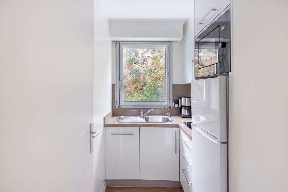Bright and compact kitchen equipped with hobs, a microwave, and a coffee maker, making meal prep a breeze.