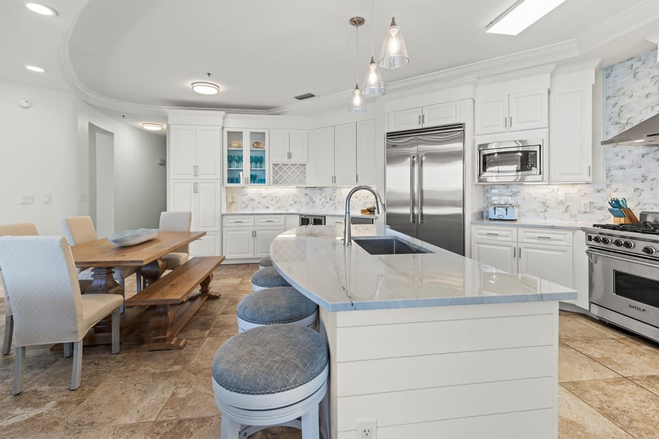 Cook together in this stunning white kitchen featuring premium appliances, marble countertops, and a spacious island perfect for morning coffee or meal prep.
