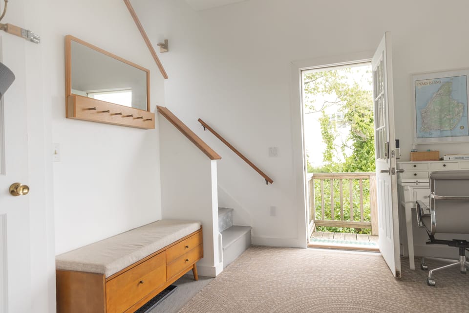 Main door and entryway with desk and desk chair. Views of ocean to the right.