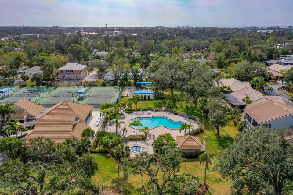 Drone shot of community clubhouse, pool, jacuzzi, and tennis/bocci ball areas
