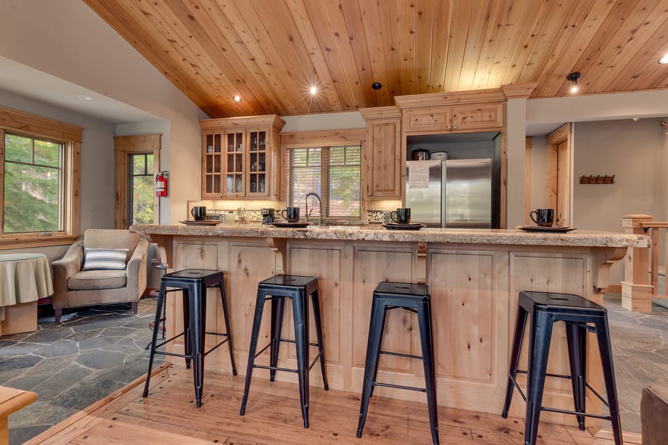 - Kitchen with bar seating and rustic wood cabinetry  
- Stainless steel appliances in this mountain cabin rental  
- Tahoe getaway with open-concept dining and cooking