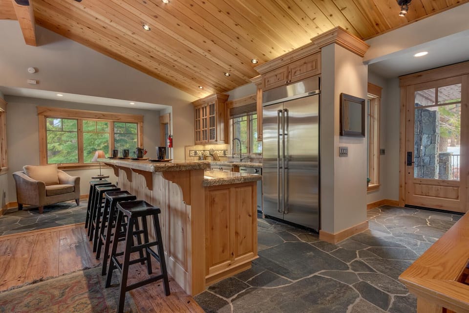 - Gourmet kitchen with stainless steel fridge and stove  
- Cabin rental with stone flooring and rustic finishes  
- Tahoe mountain home with open kitchen and seating