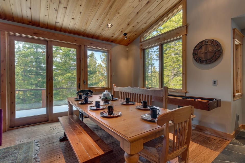 - Dining area with large wood table and bench seating  
- Surrounded by windows offering forest views  
- Tahoe vacation home perfect for group meals