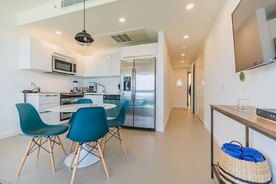 Step into your bright, modern kitchen and dining area—perfect for preparing meals and gathering around the sleek table with your travel companions.