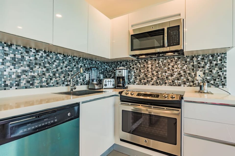 A stylish, fully equipped kitchen ready for your culinary adventures, featuring modern appliances, sleek countertops, and a vibrant mosaic backsplash that adds personality to your home away from home.