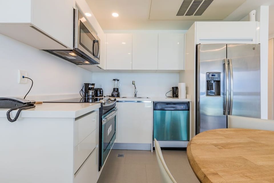 Prepare meals with ease in this sleek, fully equipped kitchen featuring stainless steel appliances, modern white cabinetry, and spacious countertops—perfect for whipping up your favorite dishes.