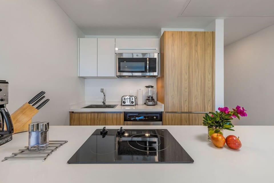 Your sleek kitchen features modern appliances, a stylish induction cooktop, and a warm wood-toned backsplash—ideal for preparing your favorite meals in style.