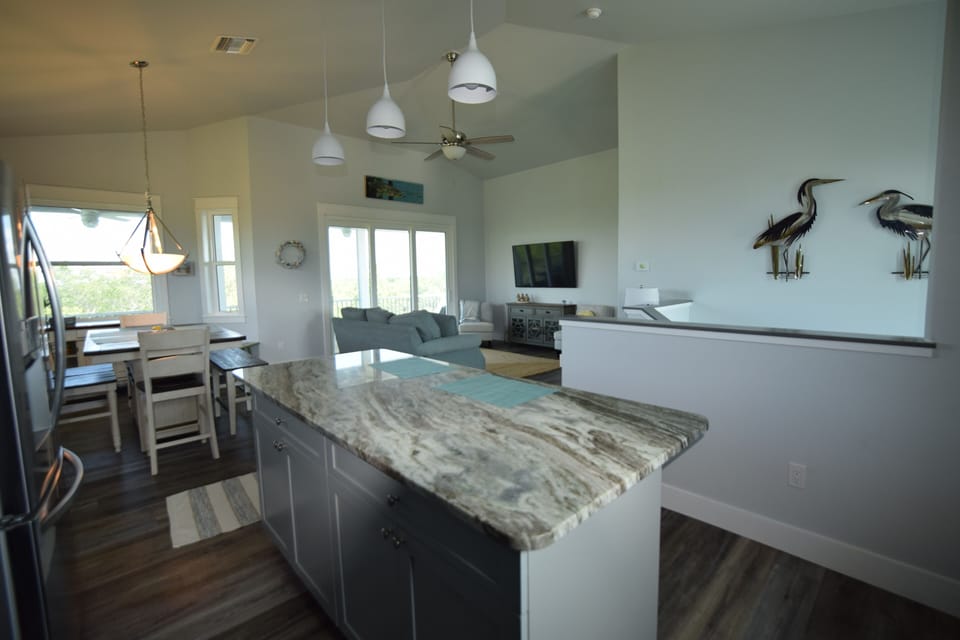 View from kitchen into family room and dining room; metal birds over stairway