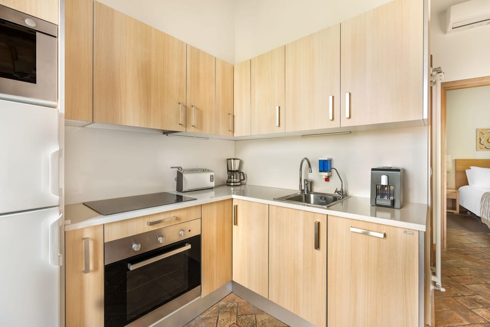 Cook with ease in a sleek, modern kitchen finished in pale wood and polished stone.