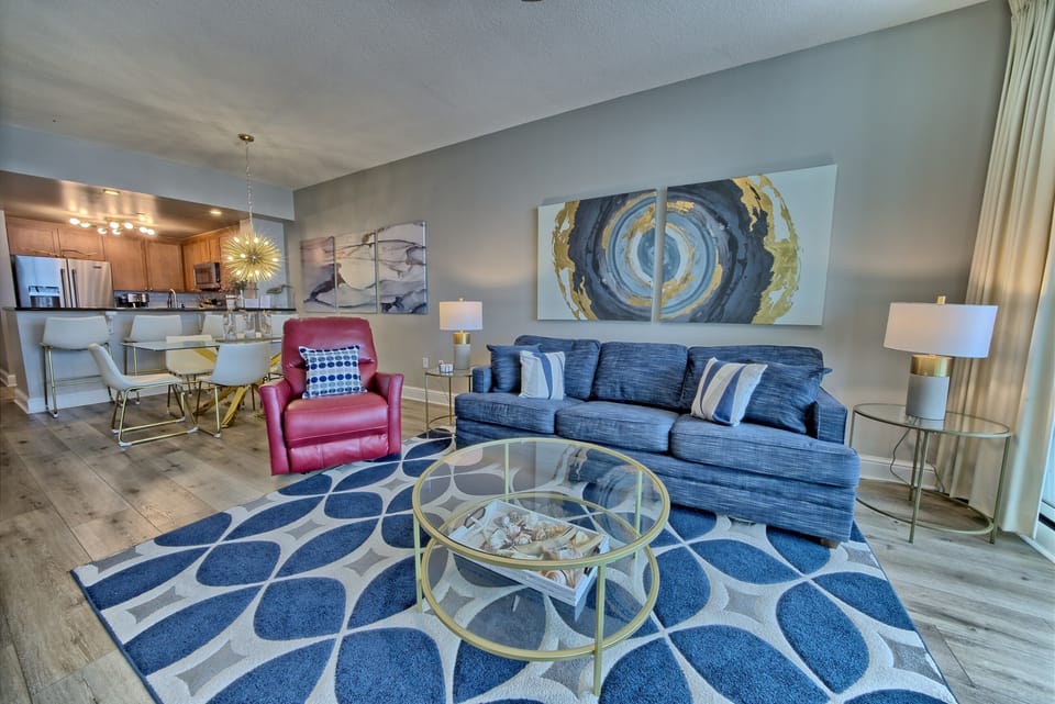 Your stylish open-plan living space features a cozy blue sofa, modern dining area, and fully-equipped kitchen—perfect for relaxing after exploring the city.