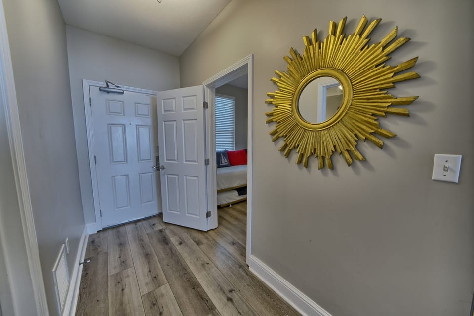 Step into your stylish hallway, where elegant sunburst decor and warm wood floors welcome you to beautifully appointed bedrooms.