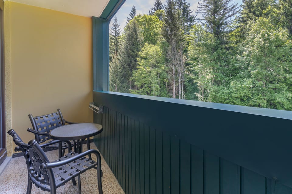 Private balcony with seating for two, overlooking lush forest views perfect for peaceful mornings or relaxing evenings.
