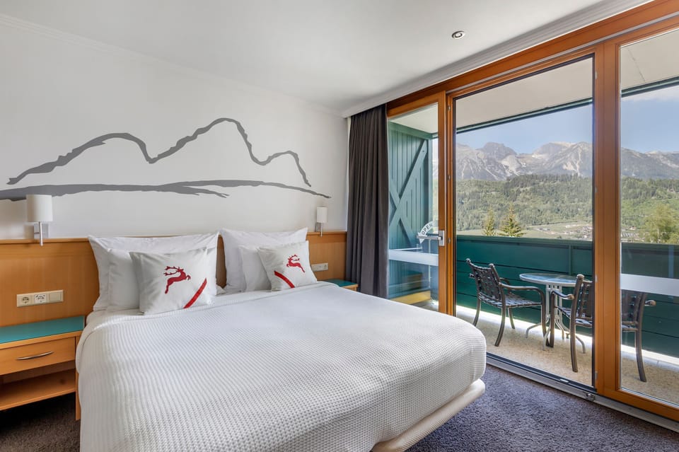 Bright, alpine-style bedroom with direct balcony access and panoramic mountain views – perfect for a peaceful morning coffee or evening unwind.