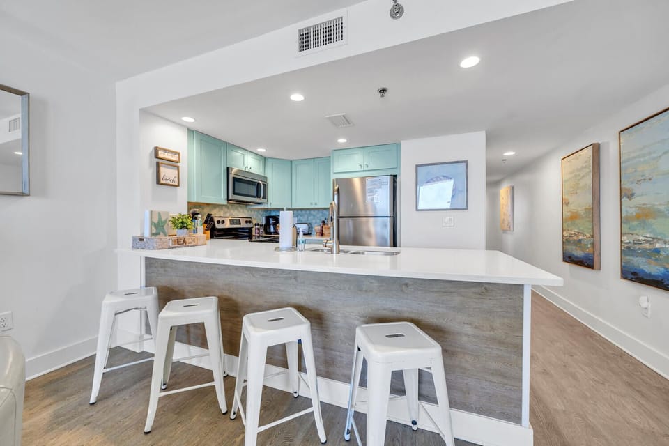 Your stylish kitchen features turquoise cabinets, pristine countertops, and modern appliances, perfect for crafting memorable meals during your stay.