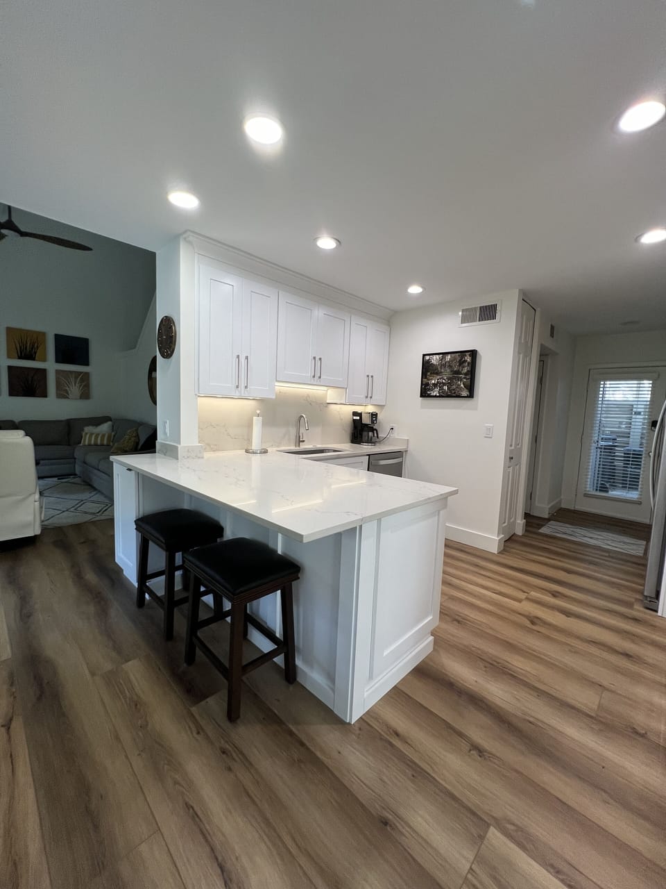 Kitchen opens to dining room, newly remodeled with counter overhang and 2 stools