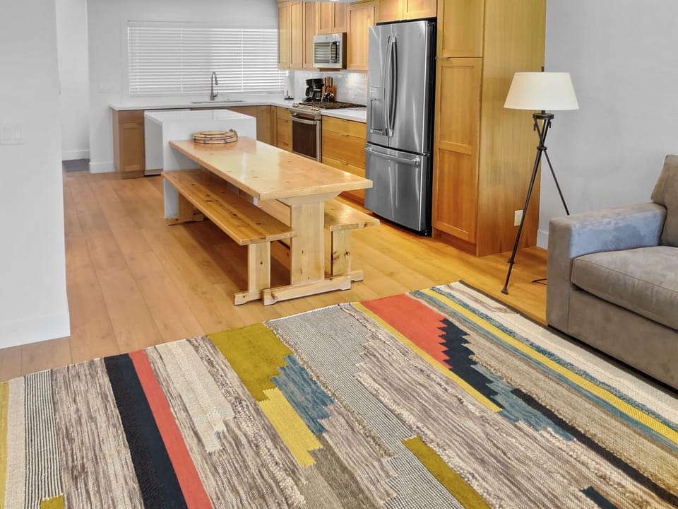 Dine with friends at the rustic wood dining table with benches, conveniently located adjacent to the fully equipped kitchen for shared meals and easy entertaining.