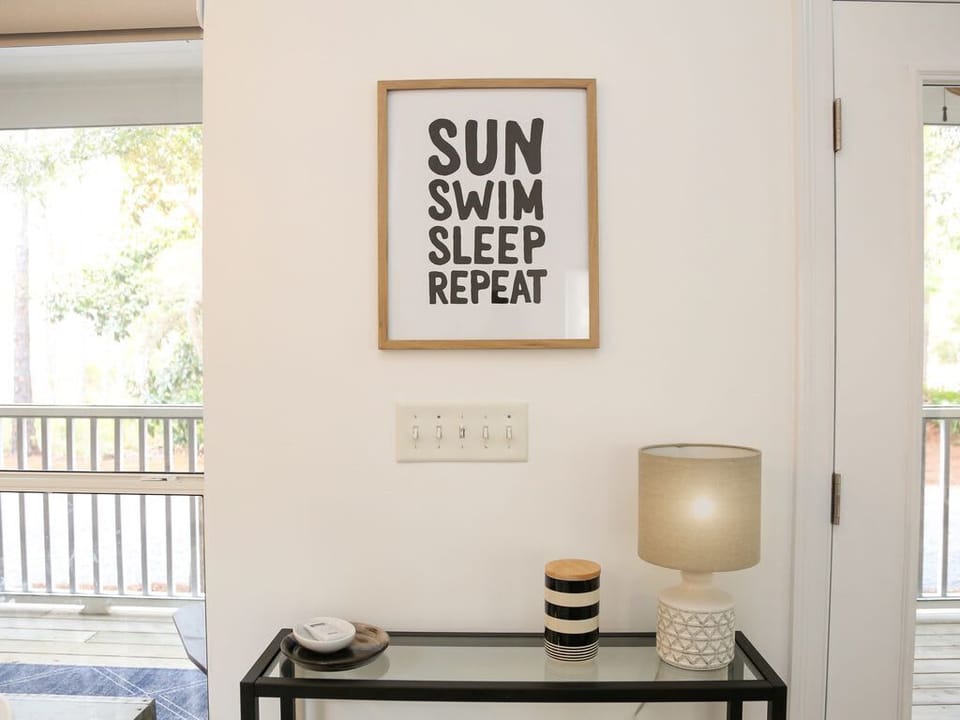 - Bright corner featuring a glass console table, textured lamp & bold art print to welcome your stay - Touch of modern charm with coastal vibes, perfect for post beach relaxation - Let the rhythm of “Sun, Swim, Sleep, Repeat” set the tone for your va