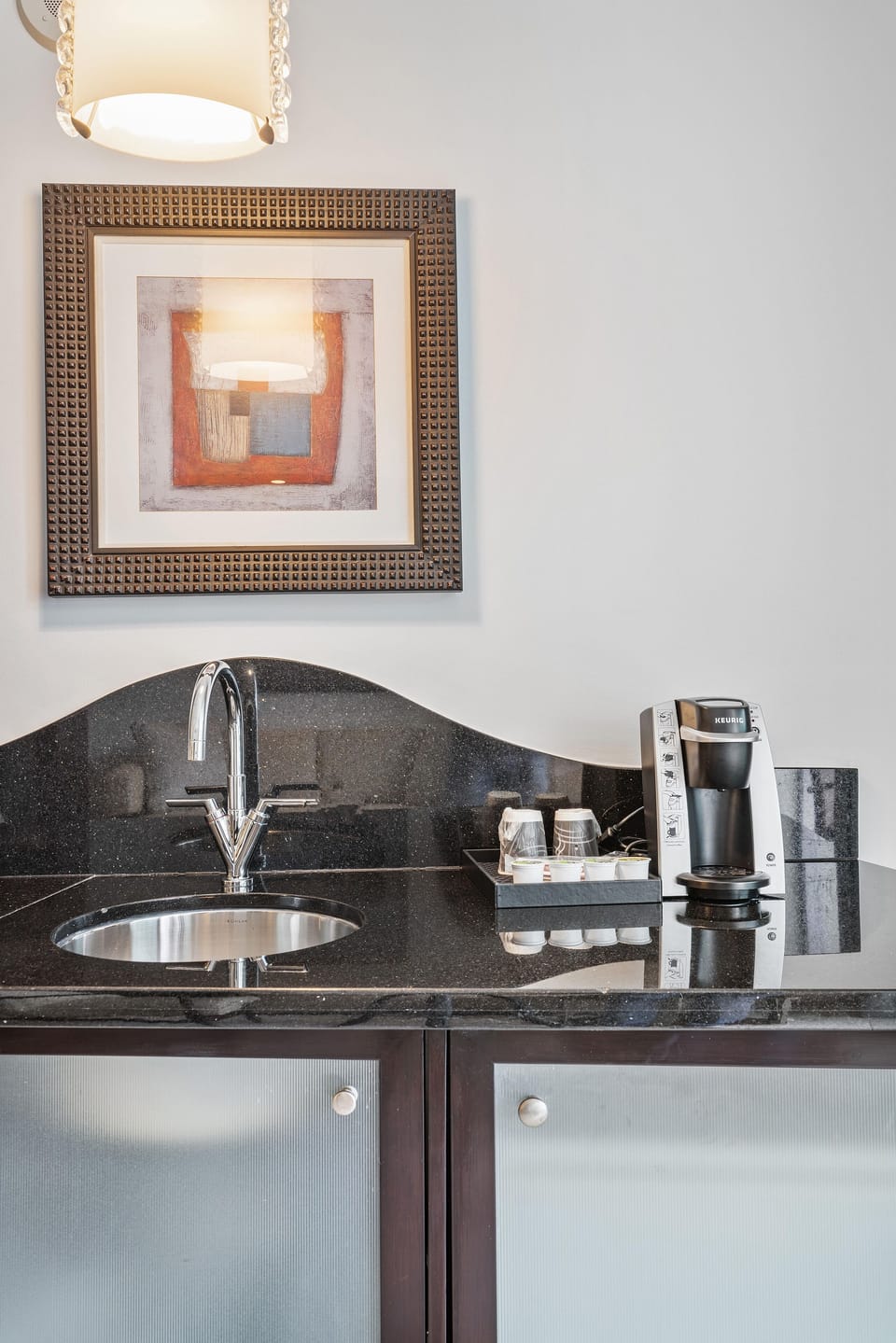 A breakfast bar with dishes, silverware, coffeemaker, microwave, toaster and mini fridge